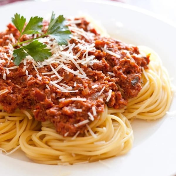 Spaghetti with rich red meat sauce, topped with grated Parmesan cheese and a sprig of parsley.