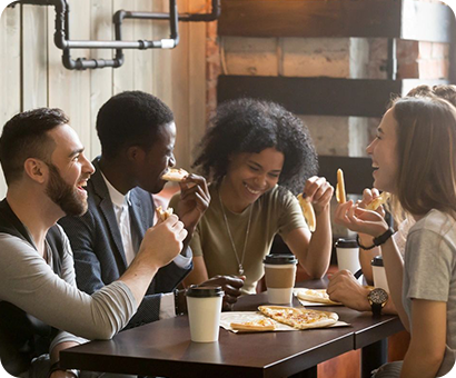 A group of people sitting at a table eating pizza.